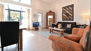Uma sala de estar com sofá, televisão e mesa de centro.