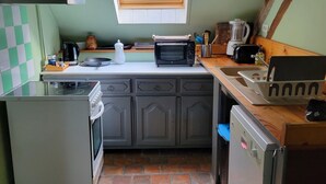 Una cocina compacta con ventana, tostadora, hervidor y licuadora en la encimera.