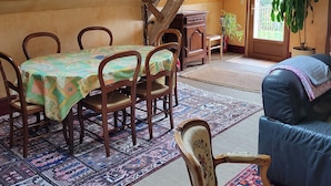 Un comedor con una mesa y sillas de madera, un tapete estampado y un ventanal con vistas a zonas verdes.