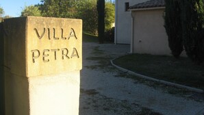 A stone sign with "VILLA PETRA" inscribed, a gravel path, and a building with a tiled roof. - 4-bedroom villa with heated private pool and large enclosed garden in Lourmarin (Lourmarin)
