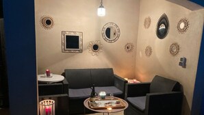 Un rincón acogedor con un sofá, una mesita con bebidas y decoración en las paredes.