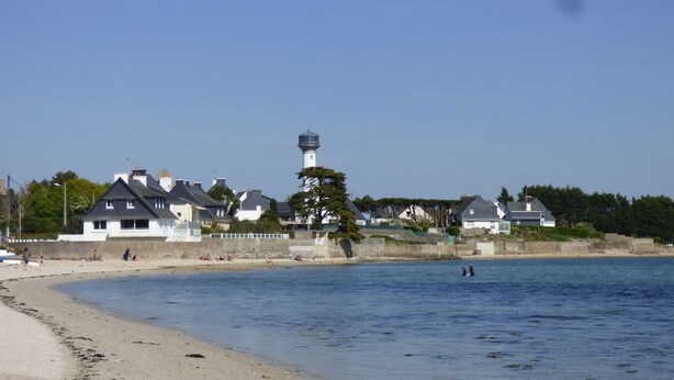 A coastal scene with a lighthouse, beach, and residential buildings. - New: ground floor house, quiet location, close to the sea (Riantec)
