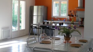 A modern kitchen with a dining area, featuring a stainless steel refrigerator, a dining table with chairs, and a window with a view of greenery. - Mazan holiday villa with private swimming pool on 3000m (Mazan)