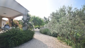 A gravel pathway leading to a covered area with a pergola, surrounded by lush greenery and flowering plants. - Mazan holiday villa with private swimming pool on 3000m (Mazan)