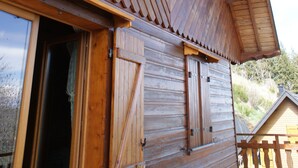 A wooden cabin with a sloped roof, a wooden door, and a window with shutters. - CHALET SUR FLANC DE COLLINE A BESSE PROMO last minute in May (Besse-Et-Saint-Anastaise)