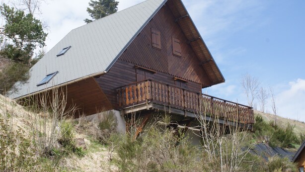 A wooden cabin with a sloped roof, a balcony, and a small window. - CHALET SUR FLANC DE COLLINE A BESSE PROMO last minute in May (Besse-Et-Saint-Anastaise)