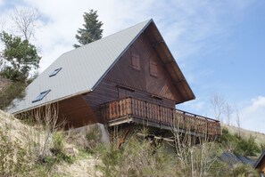Una baita di legno con tetto spiovente, un balcone e una piccola finestra.