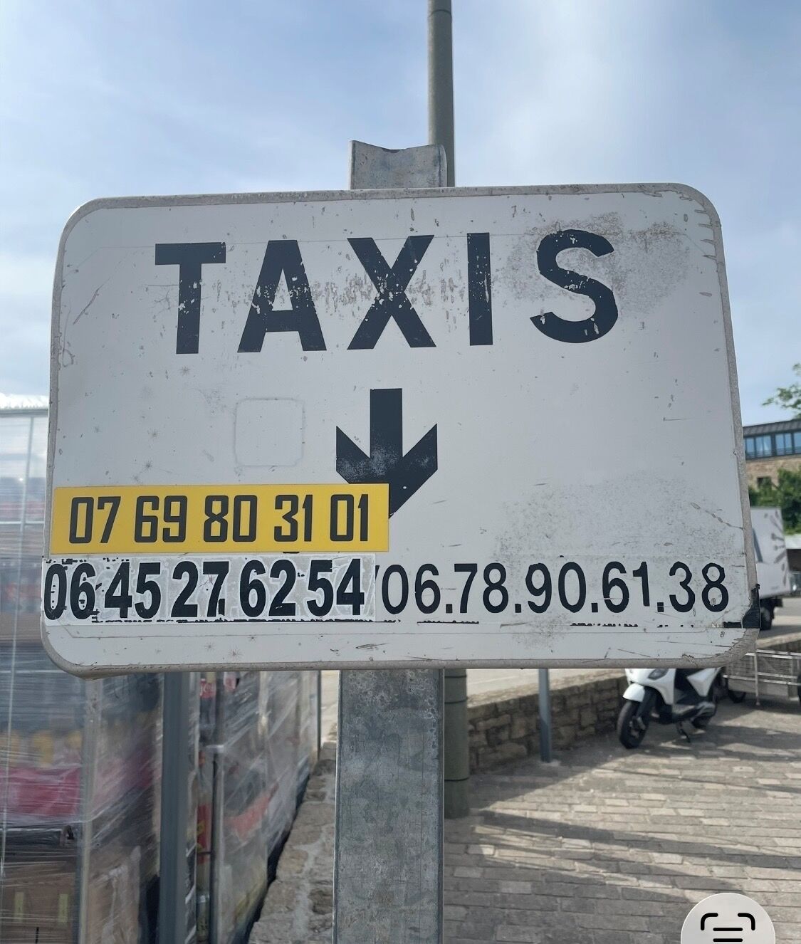 Ein Schild mit der Aufschrift 'TAXIS' und einem nach unten zeigenden Pfeil, der den Weg zum Taxistandort weist.