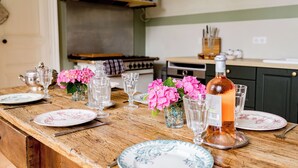 A wooden dining table set with plates, glasses, and a bottle of drink.