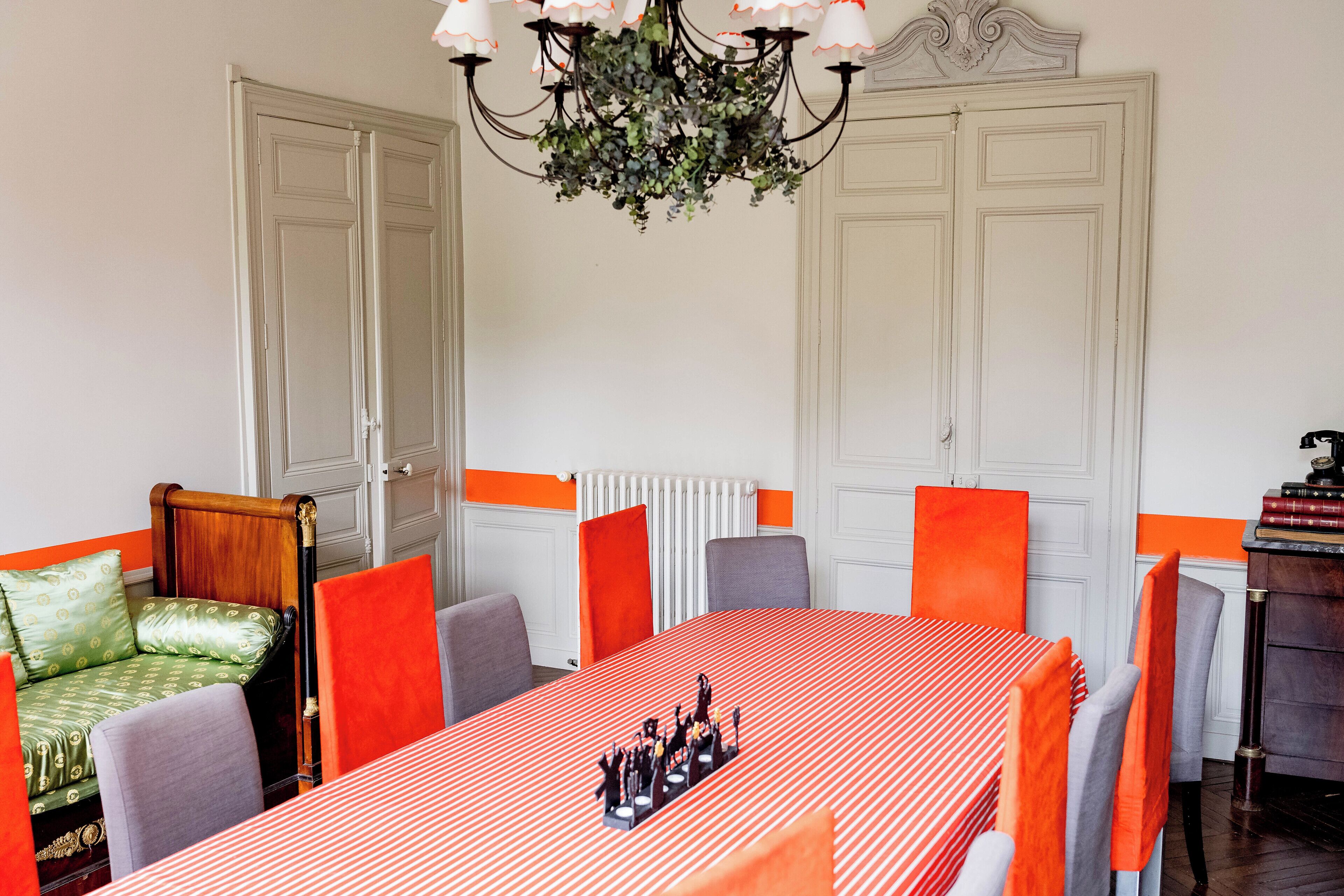 A dining area with a long table, chairs, and a chandelier.