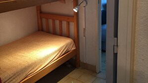 A bunk bed with a headboard, a bedside lamp, and a wall-mounted light fixture.
