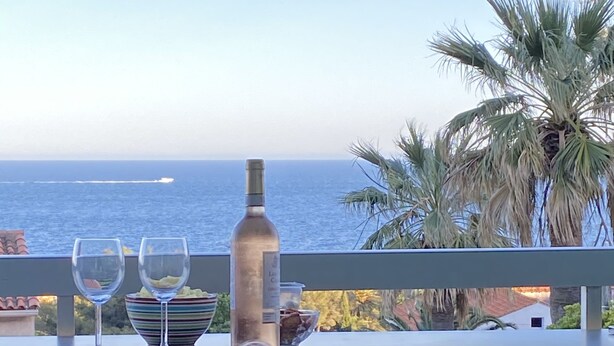 A balcony with a table set for two, overlooking the ocean.