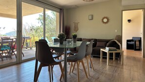 Un salon moderne avec une table à manger en verre, des sièges confortables et une vue sur l’extérieur.