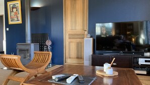 A living room with a wooden table, two wooden chairs, a fireplace, a television, and a framed picture on the wall. - Family villa for 7 people in a quiet location NEAR THE LAKE AND THE OCEAN, with a terrace and a pool table   (Gironde)