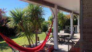 A wooden deck with a hammock, outdoor furniture, and a view of the garden. - Family villa for 7 people in a quiet location NEAR THE LAKE AND THE OCEAN, with a terrace and a pool table   (Gironde)
