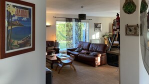 A living room with a brown leather sofa, a wooden coffee table, and a framed picture of Hawaii. - Family villa for 7 people in a quiet location NEAR THE LAKE AND THE OCEAN, with a terrace and a pool table   (Gironde)