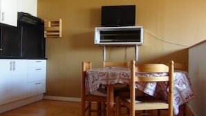 A small kitchen with white cabinets, a black range hood, and a wall-mounted air conditioner. - Large first floor studio in a peaceful building: no smoking, pets not allowed (Les Rousses)