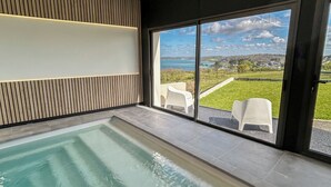Ein moderner Innenpool mit Blick auf eine grüne Landschaft durch große Fenster.