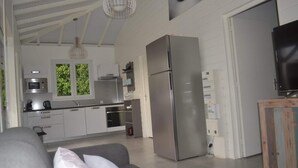 A modern kitchen with stainless steel appliances, a grey sofa, and a wooden cabinet. - THE FLAMBOYING VILLA at the estate "LES LODGES DE MALENDURE" (Bouillante)