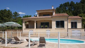 A two-story house with a swimming pool, outdoor seating, and a covered patio area. - Renting a villa with private pool in the country. (Les Salelles)