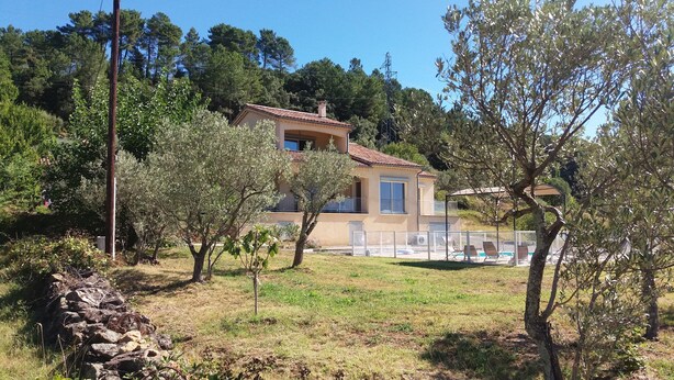 A two-story house with a tiled roof, surrounded by trees and a swimming pool with lounge chairs. - Renting a villa with private pool in the country. (Les Salelles)