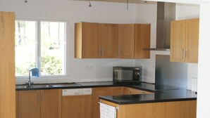 A kitchen with wooden cabinets, a microwave, and a dishwasher. - Renting a villa with private pool in the country. (Les Salelles)