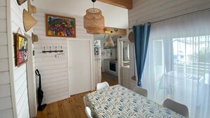 Una habitación con cama, mesa de comedor, zona de cocina y vistas al exterior por una ventana.