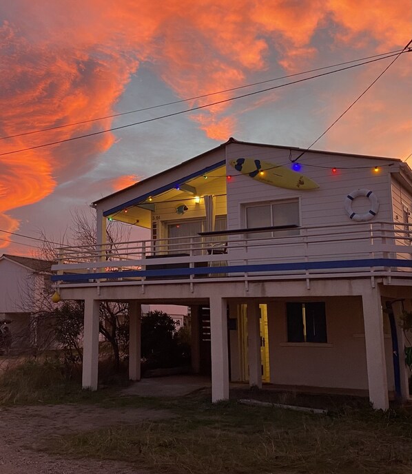 A two-story building with a balcony, a lifebuoy, and a surfboard decoration.