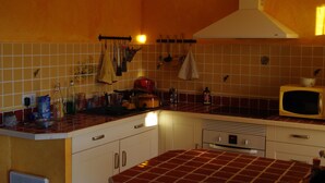 A kitchen with a tiled backsplash, a microwave, and various kitchen utensils hanging on the wall.
