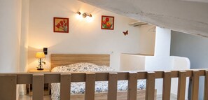 A bedroom with a wooden bed, a nightstand with a lamp, and wall-mounted light fixtures. - Le Marronnier Vacation Rental – Accessible to People with Disabilities – Mont Ventoux & Cycling (Monieux)