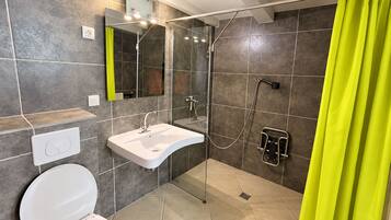 Un baño moderno con ducha, lavamanos e inodoro.