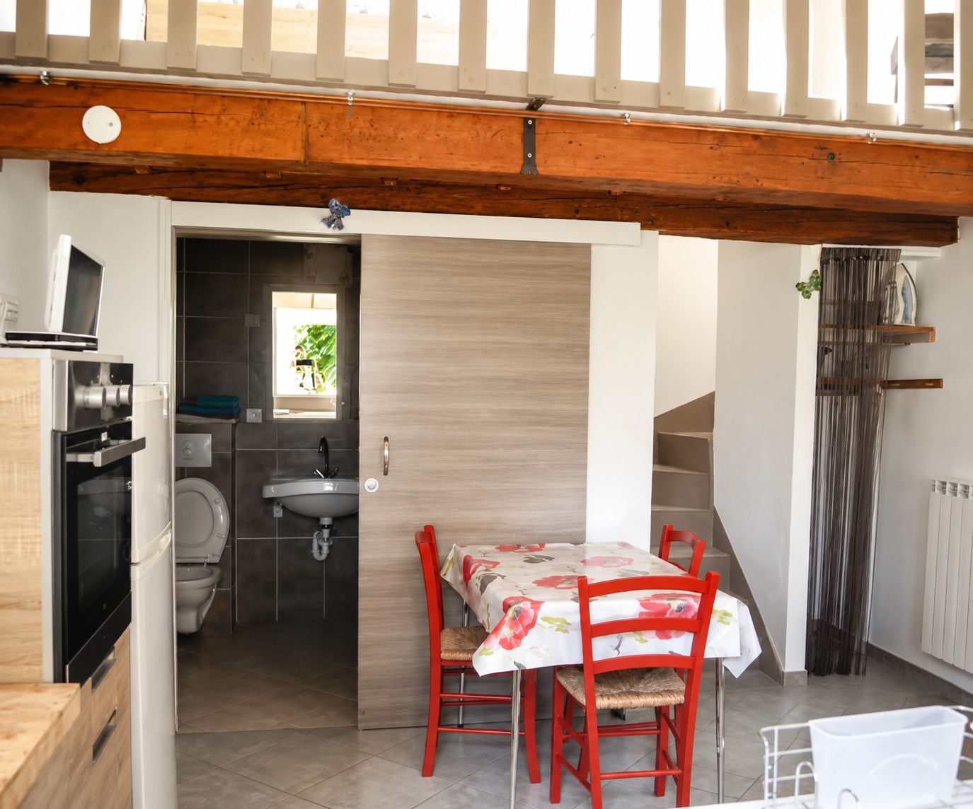 Cozinha compacta com área de refeições, vigas de madeira no teto e vista para o exterior.