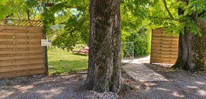 Ein verschlossenes Tor mit einem Holzzaun, einem gepflasterten Weg und einer Bank im Hintergrund.