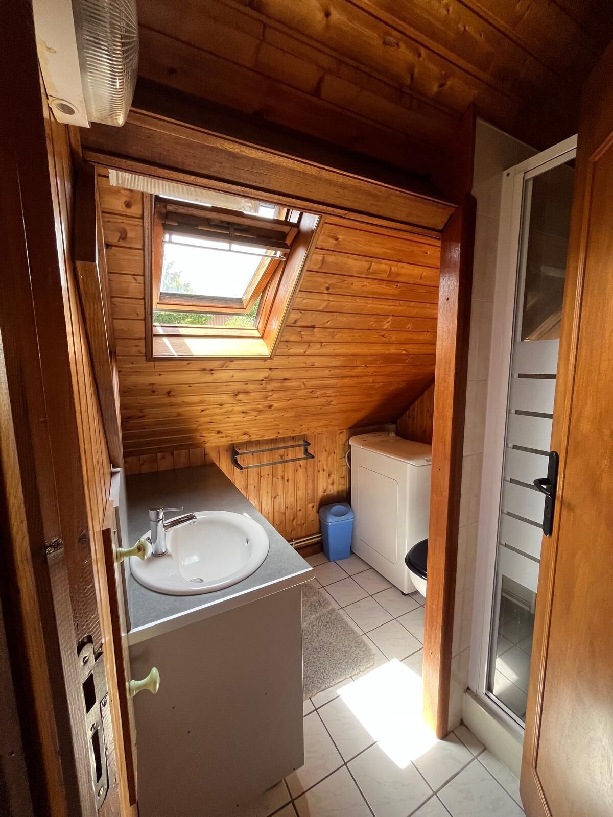 Un baño pequeño y acogedor, con paneles de madera, tragaluz, lavabo e inodoro.