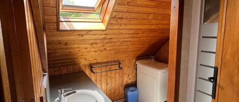 Un baño pequeño y acogedor, con paneles de madera, tragaluz, lavabo e inodoro.
