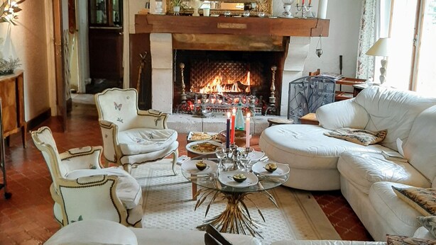 A traditional room with a fireplace, white furniture, and a decorative mirror.
