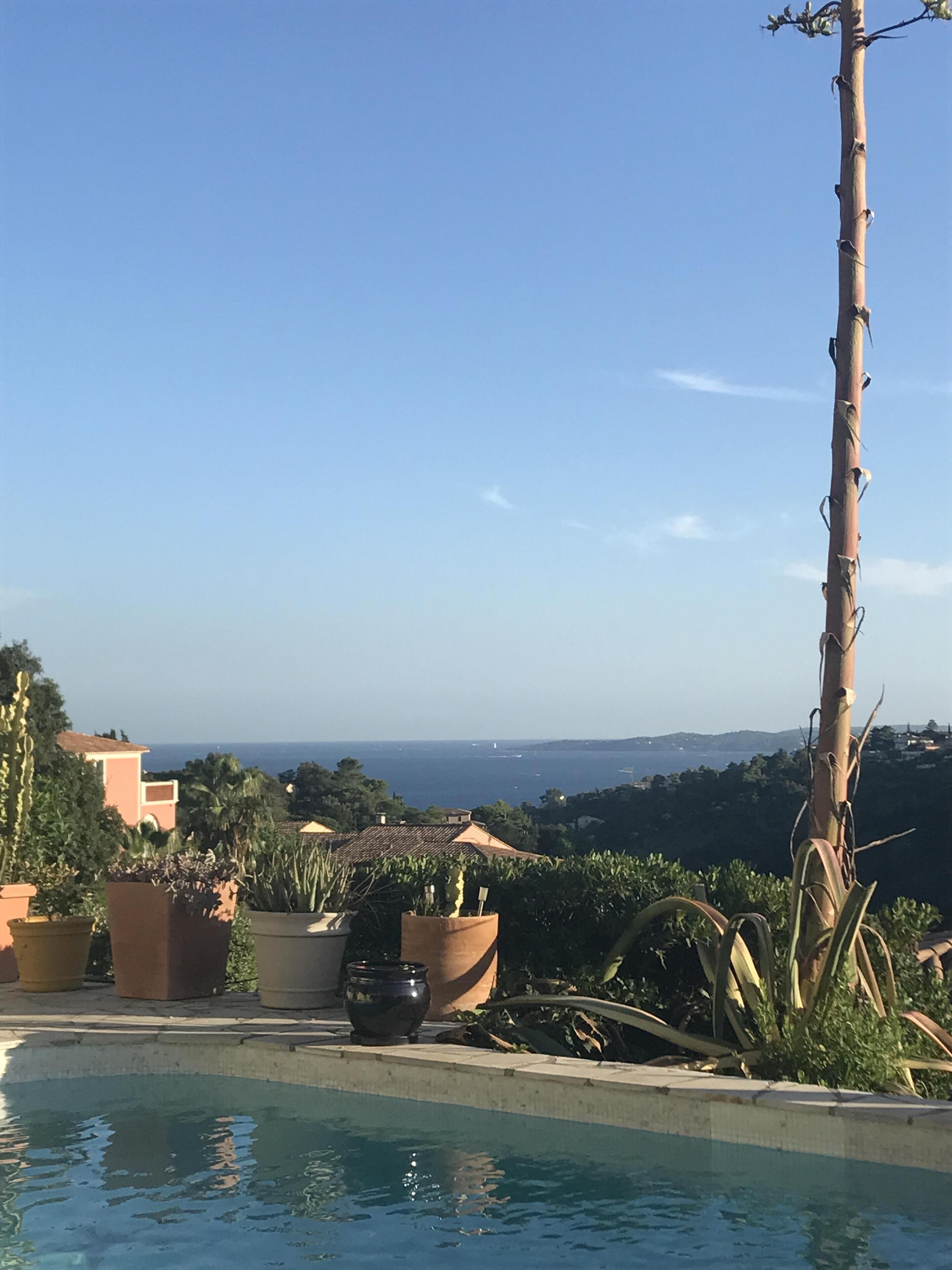 A pool with a clear view of the sea and distant hills.