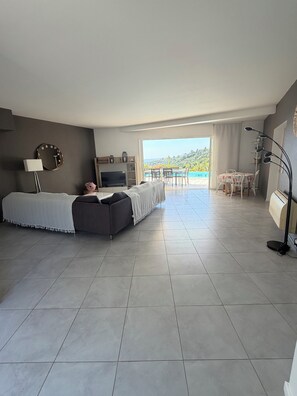 A spacious room with a bed, a TV, a dining area, and a balcony with a view. - Stunning ocean view in Les Issambres, pool, air conditioning, pétanque court, wheelchair accessible... (Roquebrune-sur-Argens)