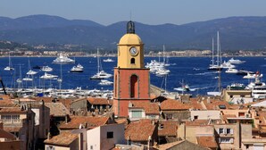 A coastal town with a prominent clock tower, numerous yachts in the marina, and terracotta-roofed buildings. - Stunning ocean view in Les Issambres, pool, air conditioning, pétanque court, wheelchair accessible... (Roquebrune-sur-Argens)