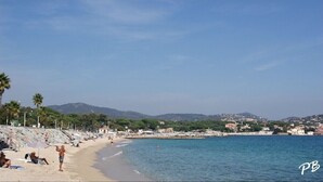 A beach with people sunbathing and swimming, a clear sky, and a distant mountain range. - Stunning ocean view in Les Issambres, pool, air conditioning, pétanque court, wheelchair accessible... (Roquebrune-sur-Argens)