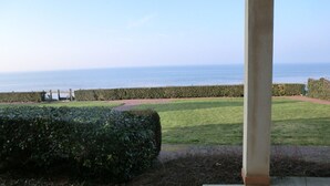 A view of a garden with a hedge, a pathway, and a body of water in the background. - Grandcamp-maisy sea view apartment, direct beach access, 4 rooms, sleeps 6 (Grandcamp-Maisy)