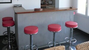 A kitchen with a bar area, including a counter and four stools. - Grandcamp-maisy sea view apartment, direct beach access, 4 rooms, sleeps 6 (Grandcamp-Maisy)