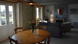 Un coin repas avec une table et des chaises en bois, un vase rempli de fleurs et un canapé en arrière-plan.