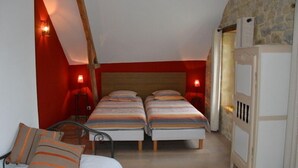 Une chambre avec deux lits, un plafond en bois et un mur en pierre.