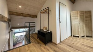 A room with a wooden floor, a black bench, a white door, and a wooden wardrobe.