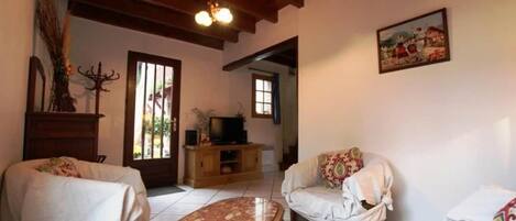 A cozy living room with a wooden ceiling, a television on a wooden stand, a sofa, and a coffee table.