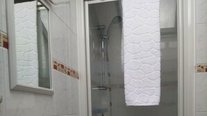 A bathroom with a white sink, a mirror, a shower, and a towel hanging on the wall. - 4-person apartment (Docelles)