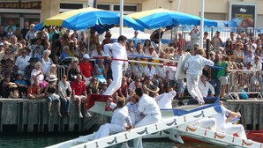 Een bootrace met toeschouwers en deelnemers op de kade.