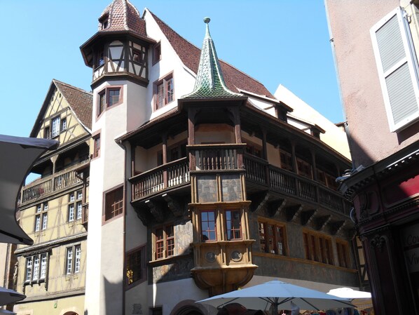 A historic building with a turret, a balcony with a balustrade, and a clock tower.