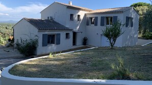 A two-story house with a tiled roof, a small garden, and a driveway.